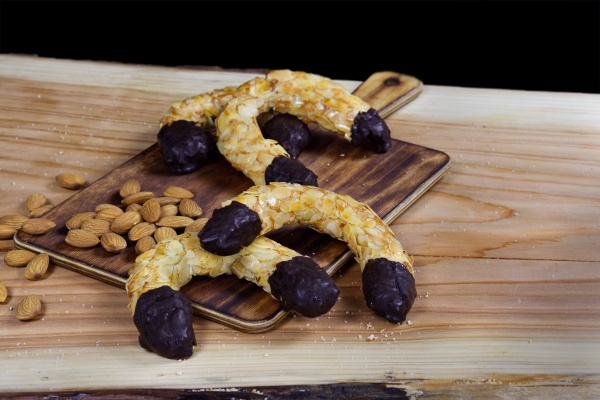 Crujiente mazapán espolvoreado con almendra laminada y puntas bañadas de chocolate. En forma de herradura de la suerte. ¡Suerte para quien la coma!